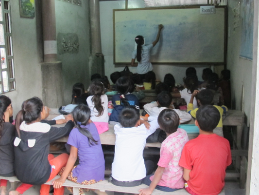 Students in an indoor classroom being taught by KCEO teacher Sokhi.